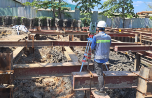 Kỹ sư xây dựng kiểm tra bản vẽ thiết kế nhà xưởng tại hiện trường công trình thực tế